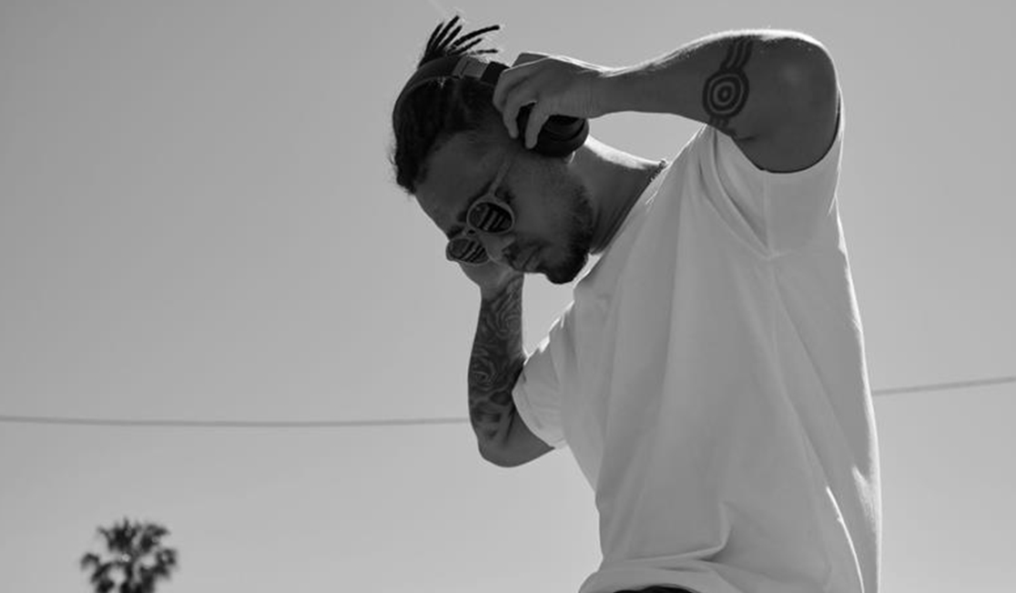 A black and white photo of a man in a white t-shirt listening to headphones.