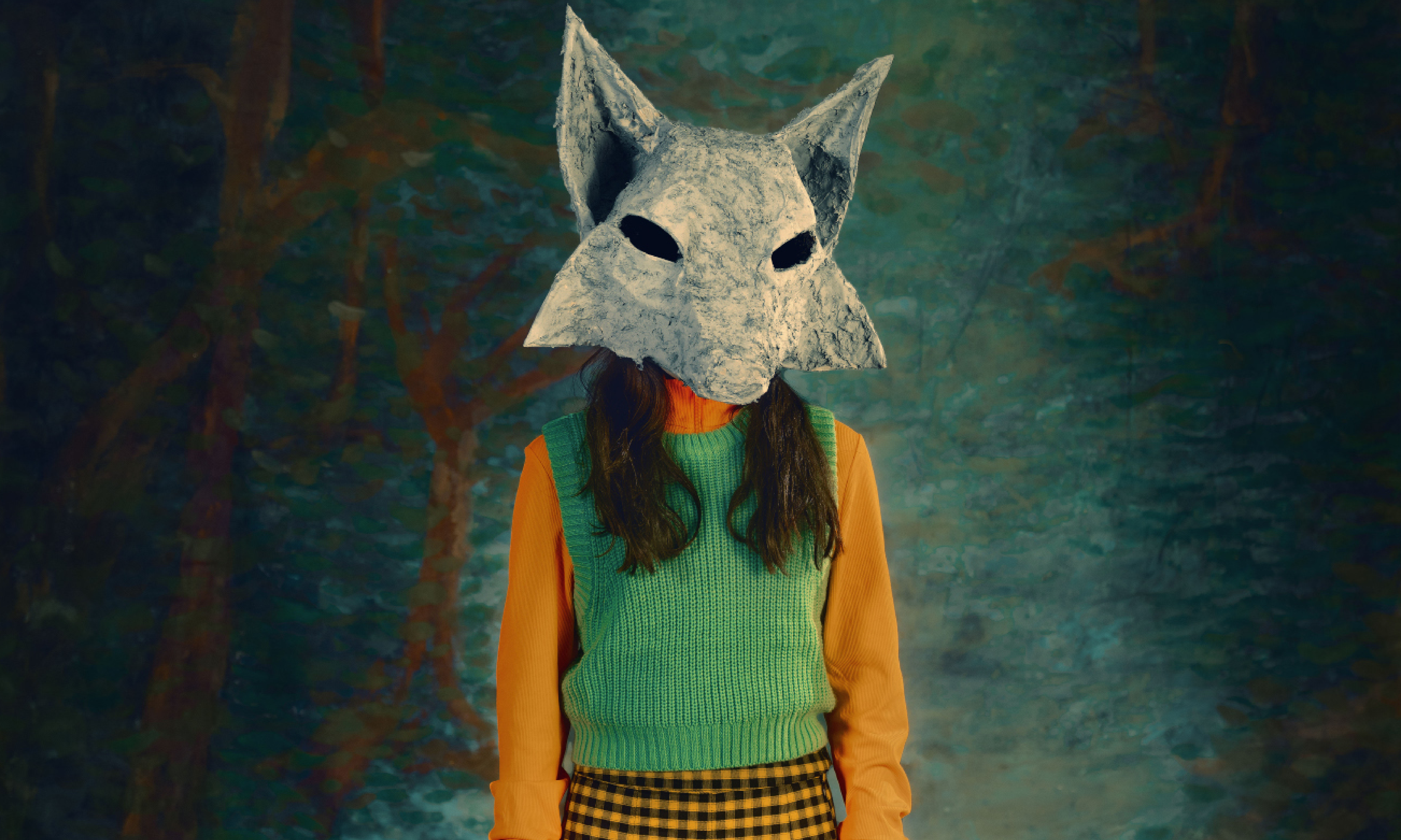 A video of a girl wearing a wolf mask, a green vest and a yellow checked shirt. She is moving only slightly and the lighting is very dark.